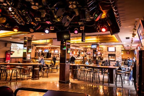 a bar with tables and chairs in a restaurant at Curtis Gordon Motor Hotel in Winnipeg