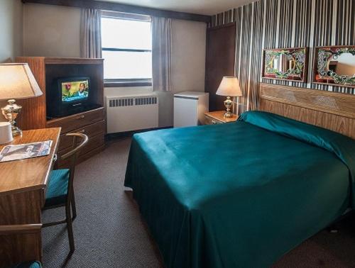 Habitación de hotel con cama y TV en Curtis Gordon Motor Hotel, en Winnipeg