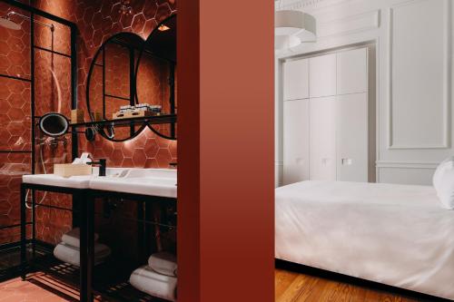 a bathroom with a sink and a bed and a mirror at The Bold Type Hotel, a Member of Design Hotels in Patra