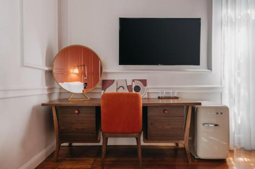 a desk with a chair and a television on a wall at The Bold Type Hotel, a Member of Design Hotels in Patra