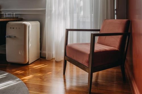 a chair and a refrigerator in a room at The Bold Type Hotel, a Member of Design Hotels in Patra