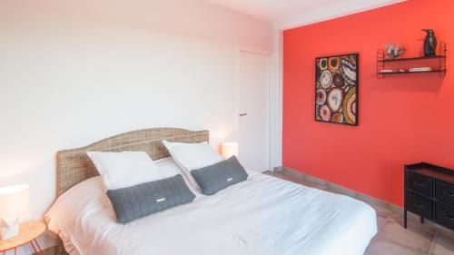 a bedroom with a red wall and a bed with two pillows at Les Vagues avec Jacuzzi Privatif & Parking Privé in Sarlat-la-Canéda