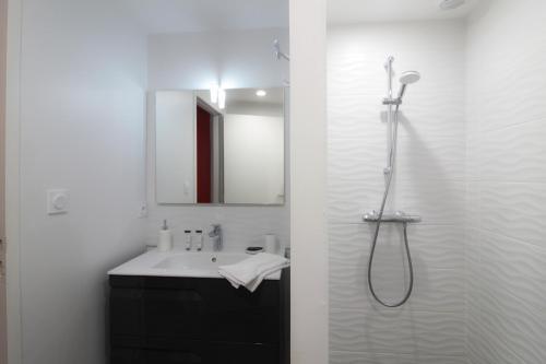 a white bathroom with a shower and a sink at Les Vagues avec Jacuzzi Privatif & Parking Privé in Sarlat-la-Canéda