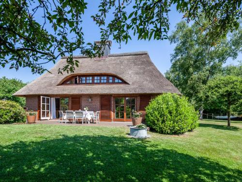 a thatch roofed house with a patio at Ferienhaus REETselig mit Pool Sauna in Klein Barkau