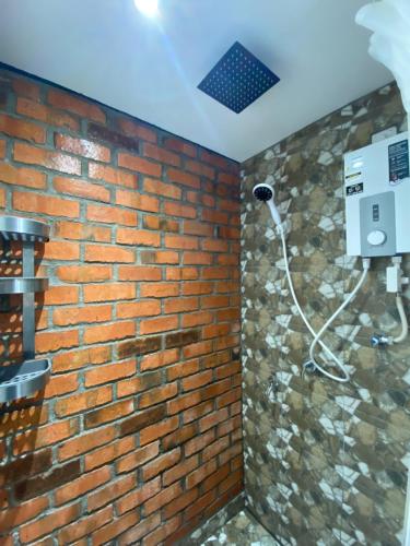 a bathroom with a brick wall with a shower at Grand Lodge Langkawi in Pantai Cenang