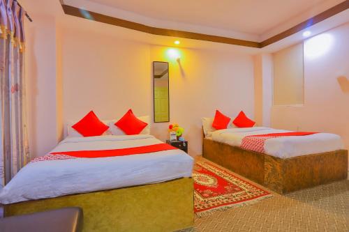 a bedroom with two beds with red pillows at OYO 656 Hotel Shree Guru in Kathmandu