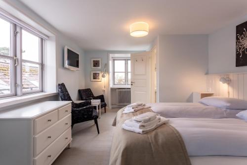a white bedroom with two beds and a chair at Rødvig Kro og Badehotel in Rødvig