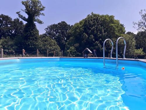 ein Swimmingpool mit blauem Wasser in einem Park in der Unterkunft Ker Jerome - Traditional Stone Breton Cottage near to Dinan in Trélivan