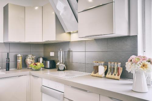a kitchen with white cabinets and flowers in a vase at Holiday house Vedrana, Jadreški in Pula