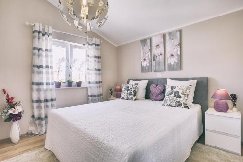 a bedroom with a white bed with pillows and a chandelier at Holiday house Vedrana, Jadreški in Pula