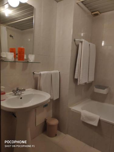 a bathroom with a sink and a toilet and a mirror at Hotel Alnacir in Faro