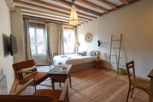 um quarto com uma cama, uma mesa e cadeiras em Les Nids Perchés - Place Notre-Dame em Mortagne-au-Perche