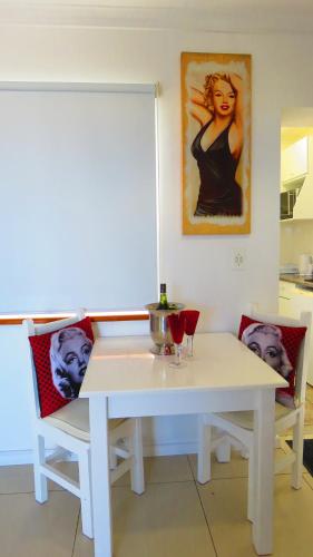 a white table with two chairs and a painting on the wall at On The Beach Apartments in Yzerfontein