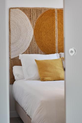 a bedroom with a bed with white sheets and yellow pillows at Slow Home Apartments in Valencia