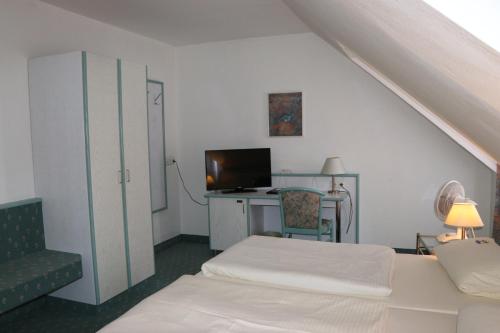 a room with a bed and a desk with a television at Hotel Windfelder in Stegaurach
