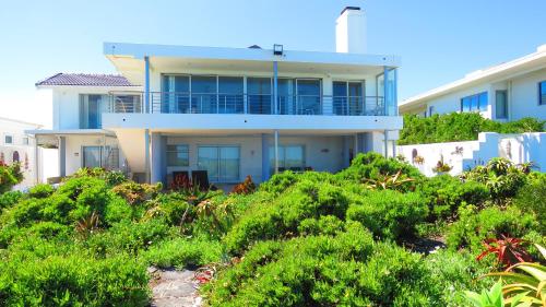 a house on the beach with bushes in front of it at On The Beach Apartments in Yzerfontein
