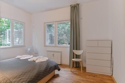 una camera da letto con un letto, una sedia e finestre di Bright Apartment in the Heart of the City by Flat Mаnager a Sofia