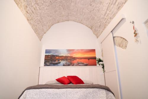 - une petite chambre avec un lit et des oreillers rouges dans l'établissement Room 20 - Piccola Camera in pietra bianca, à Giovinazzo