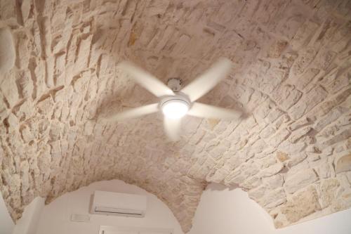 Cette chambre dispose d'un ventilateur de plafond et d'un mur en pierre. dans l'établissement Room 20 - Piccola Camera in pietra bianca, à Giovinazzo