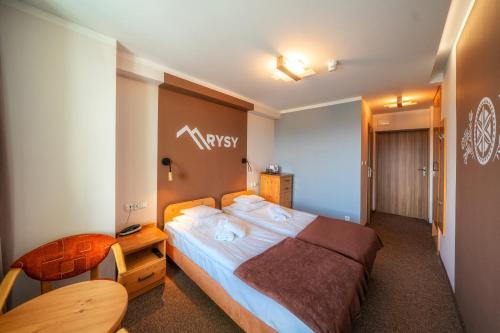 a hotel room with a large bed and a table at Rysy in Bukowina Tatrzańska