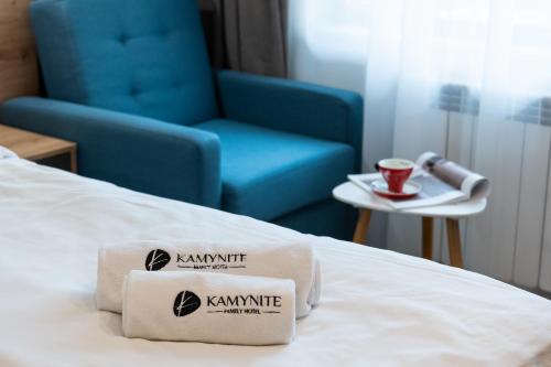 a hotel room with two towels on a bed and a chair at Хотел Камъните in Burgas