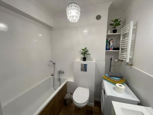a white bathroom with a toilet and a sink at Sweet Apartment in Szczecin