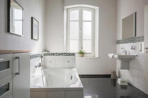 a white bathroom with a tub and a sink at Ferienhof Büdlfarm - Bauers Haus in Sahrensdorf