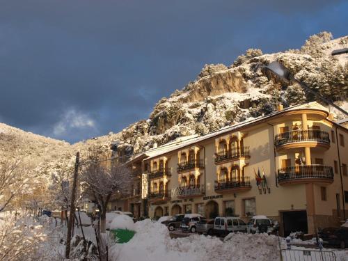 a building in the snow with a mountain at Hotel El Curro in Burunchel
