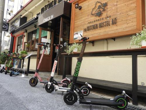 een rij scooters geparkeerd voor een winkel bij The Kitchen Hostel Ao in Naha