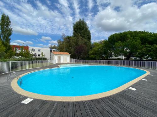 une grande piscine bleue sur une terrasse en bois dans l'établissement Le Pontappart, à Royan