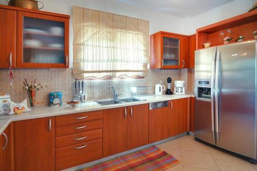 a kitchen with wooden cabinets and a stainless steel refrigerator at Welcoming villa in Triopetra with pool in Triopetra