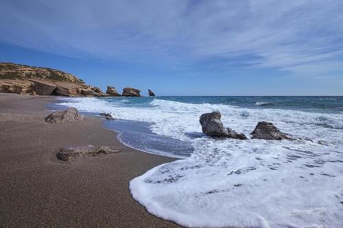 a beach with rocks in the water and the ocean at Welcoming villa in Triopetra with pool in Triopetra