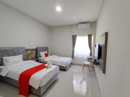 a hotel room with two beds and a television at RedDoorz Syariah near GOR Satria Area in Purwokerto