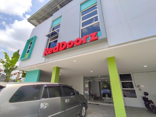 a minivan parked in front of a red door store at RedDoorz Syariah near GOR Satria Area in Purwokerto