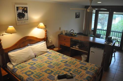 a bedroom with a bed with a dresser and a desk at The Fig Tree B&B in Baudin Beach