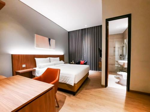 a hotel room with a bed and a bathroom at Votel Krakatau Boutique Hotel Semarang in Semarang