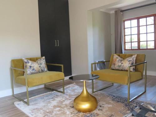a living room with two chairs and a table at Sani Pass Manor Guest House in Himeville
