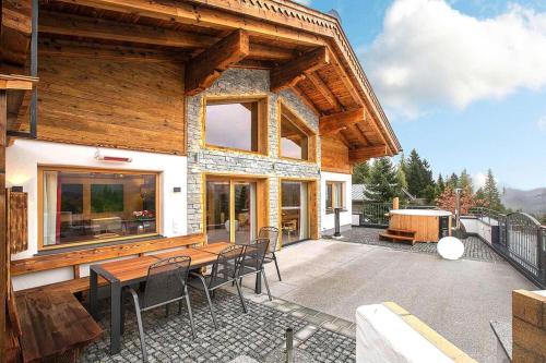 a wooden house with a table and chairs on a patio at Chalet in Königsleiten with Mountain Views & Spa in Königsleiten