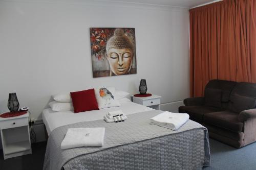 um quarto com uma cama, uma cadeira e uma máscara em Alexander Motel em Warwick