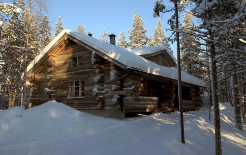 una cabaña de madera en la nieve con nieve en Viprakka, en Levi