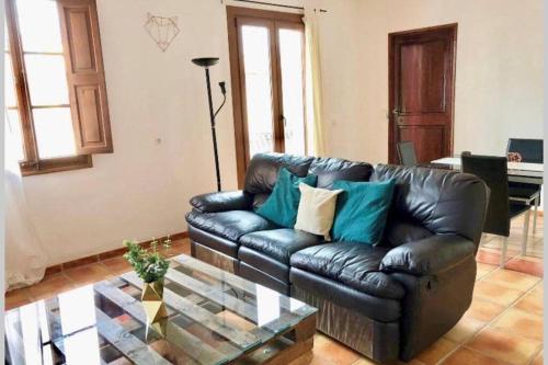 a leather couch in a living room with a glass table at Apartamentos Hostalets in Palma de Mallorca