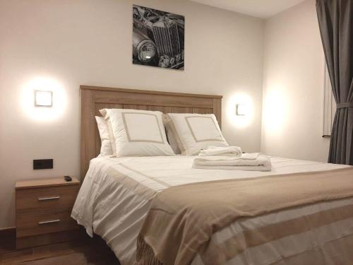 um quarto com uma cama grande com lençóis brancos e almofadas em Habitacion cerca del Aeropuerto em Coslada