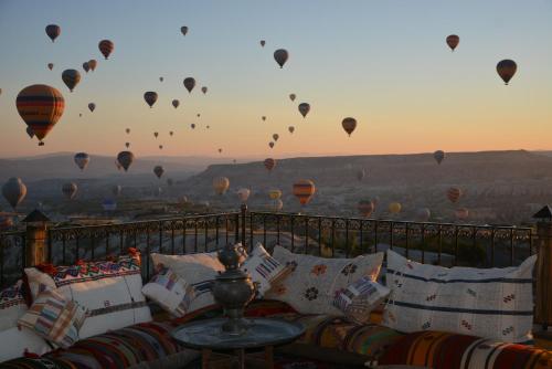 a balcony with a couch and hot air balloons in the sky at Hotel Lalesaray in Uchisar