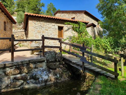a wooden bridge over a pond in front of a building at Cascata do Varosa - Turismo Rural in Vila Pouca