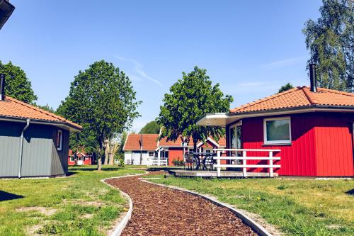 a red house with a red fence in a yard at Regenbogen Boltenhagen in Boltenhagen