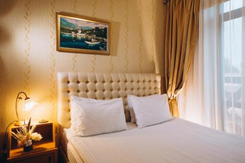 Un dormitorio con una cama con sábanas blancas y una ventana. en Готельна Ресторація "Україночка", en Krivoy Rog