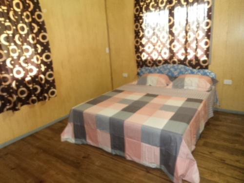 a bedroom with a bed with a checkered blanket and a window at Impeccable 1 Bedroom 4 unit Apartment in Savusavu in Savusavu
