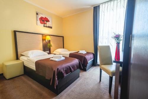 a hotel room with two beds and a chair at Casino & Hotel ADMIRAL Ptuj in Ptuj