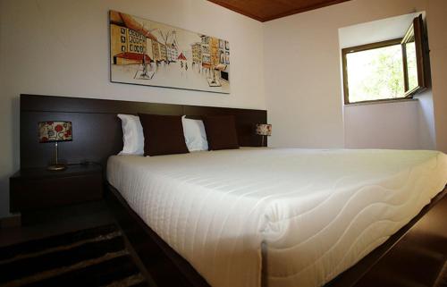 a bedroom with a large white bed with a window at Cascata do Varosa - Turismo Rural in Vila Pouca