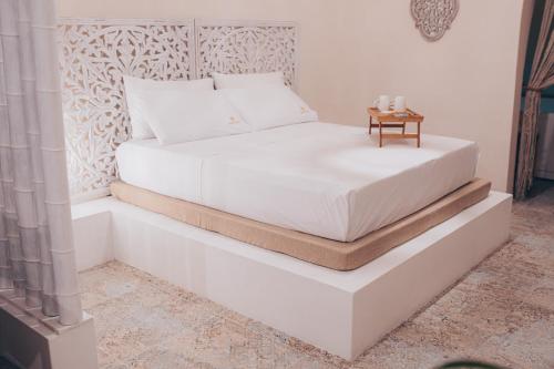Amira 1899 Luxury Suite في غالاتينا: غرفة نوم مع سرير أبيض مع طاولة عليها
